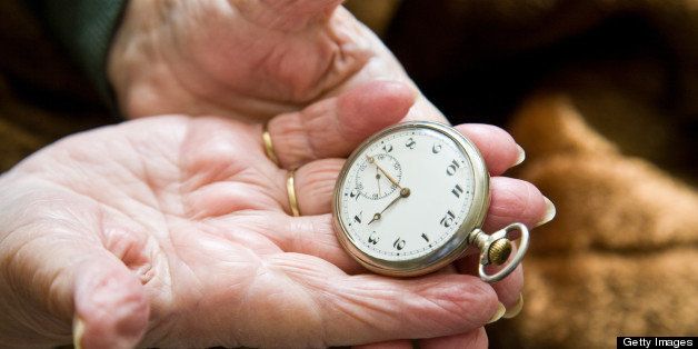 Old hands holding a silver pocket watch