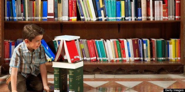 Boy (5-7) playing on floor with books in libary