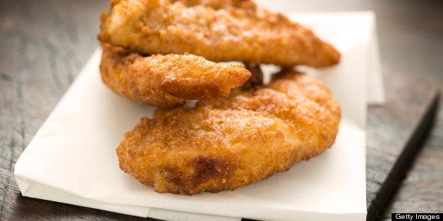 Fried Chicken Fillets on grease proof paper against old rustic wood background.