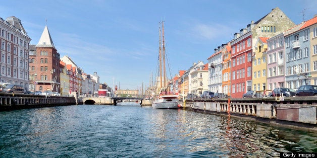Looking down one of the many branches of the Nyhavn canal in Copenhagen with colorful buildings lining the streets against a clear sky.