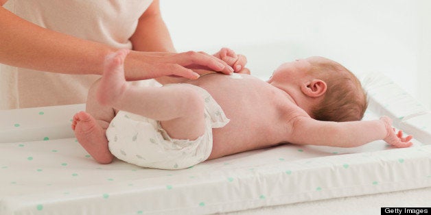 Mother changing babys diaper on changing table