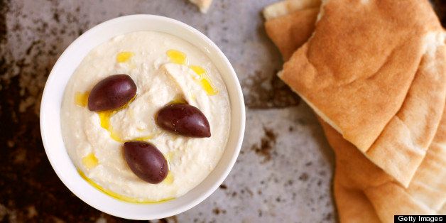 Homemade hummus drizzled with olive oil, topped with kalamata olives, and served with pita.