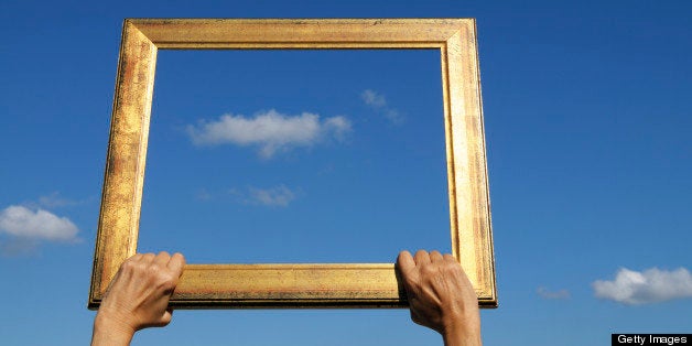 Woman holding an old frame against a blue cloudy sky. Blurred background