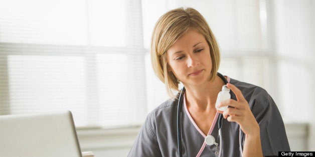 Caucasian nurse looking at medicine bottle