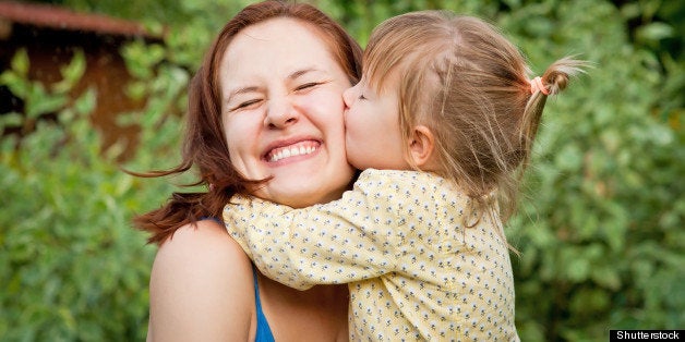 Happy young woman being kissed by a cute little girl