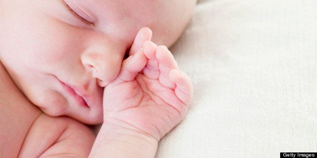 Newborn baby hand by face