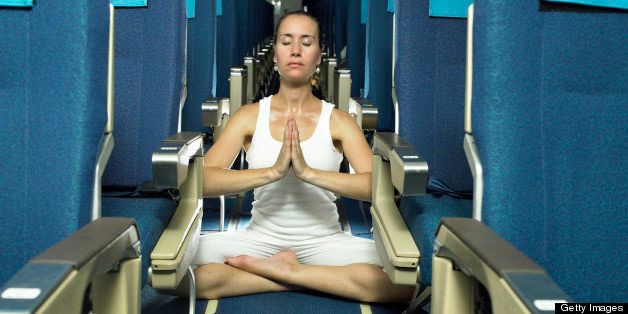 Woman meditating in aisle of airplane