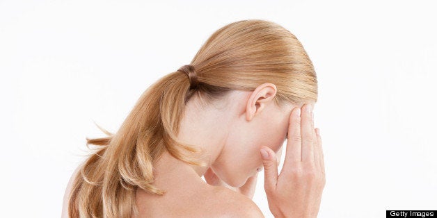 Mid adult woman touching temples against white background