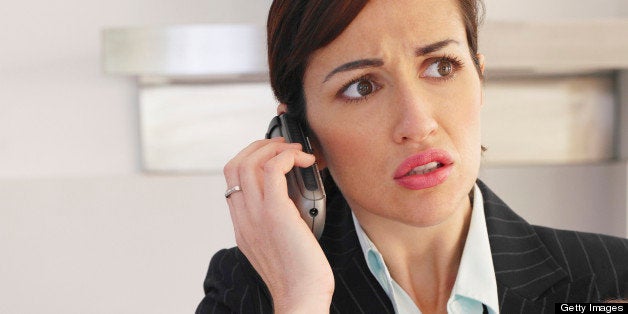 Businesswoman talking on phone holding sleeping baby