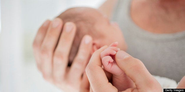 Mother cradling newborn baby's hand