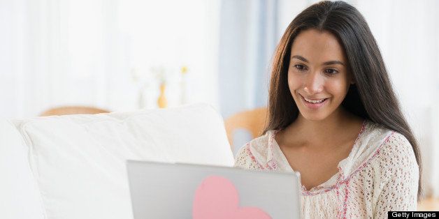 Hispanic teenager using laptop in bedroom
