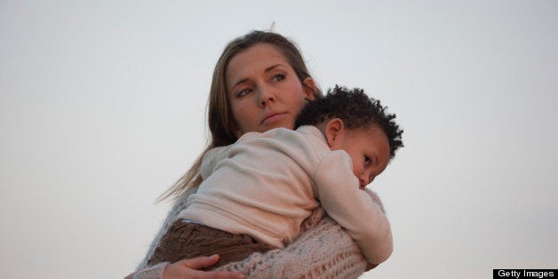 Woman holding her son at sunset