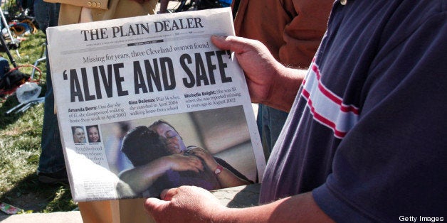 CLEVELAND, OH - MAY 7: A man shows page one of The Plain Dealer newspaper to a friend while people gather along Seymour Aven