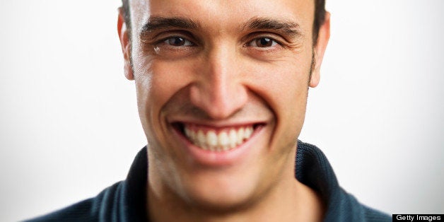 Young latin man smiling. White background. Sharp focus on eyes.