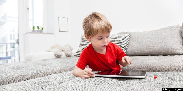 a Two year old boy playing with a digital tablet Pc at home on the couch