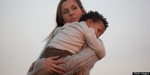 Woman holding her son at sunset