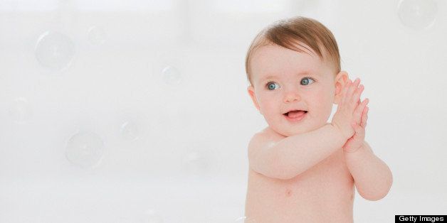 Smiling baby playing with bubbles on floor