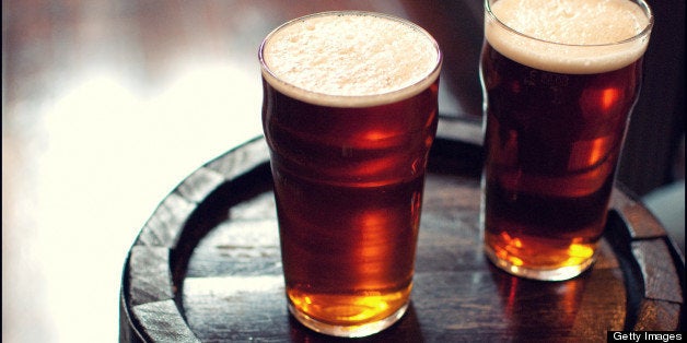 Two pints of beer bitter on wooden barrel in London pub.