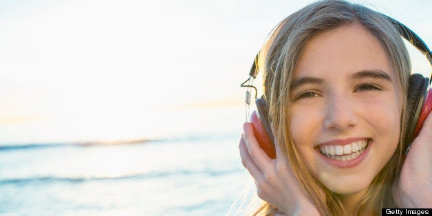 Portrait of happy pre-adolescent girl listening to music at beach