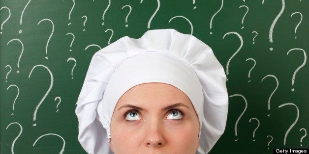 female chef thinking in front of question marks written blackboard