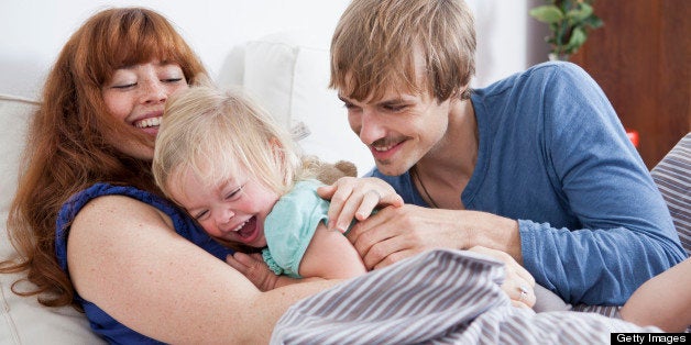 A young family having playful fun in bed