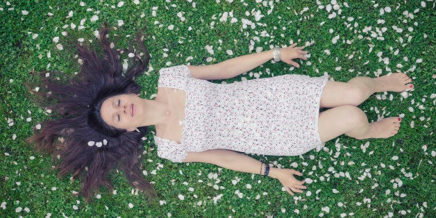 Young woman in a meadow full of apple petals - from above - image cross processed