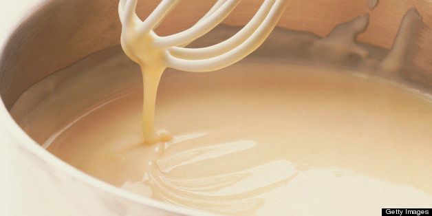 Close-up of bechamel white sauce on a metal whisk.