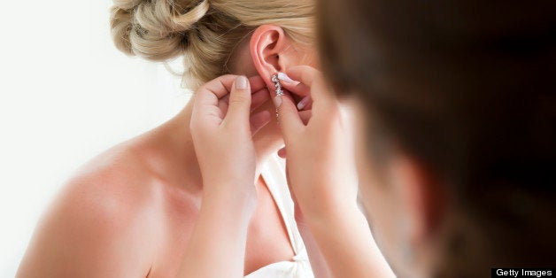wedding bride putting on earring and jewelery