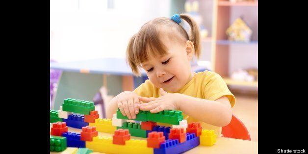 Cute little girl play with building bricks in preschool