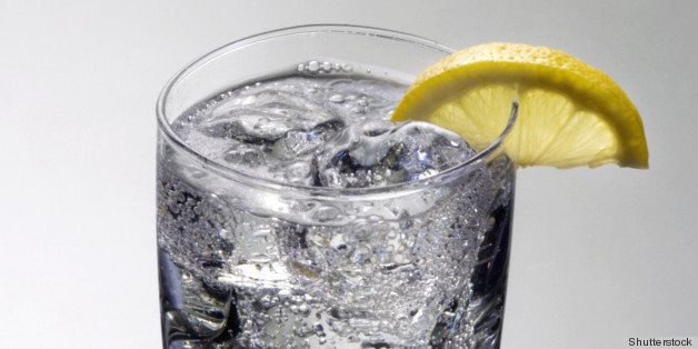 Club soda or Vodka / Gin and tonic mixed drink with lemon slice on a gray background with reflection
