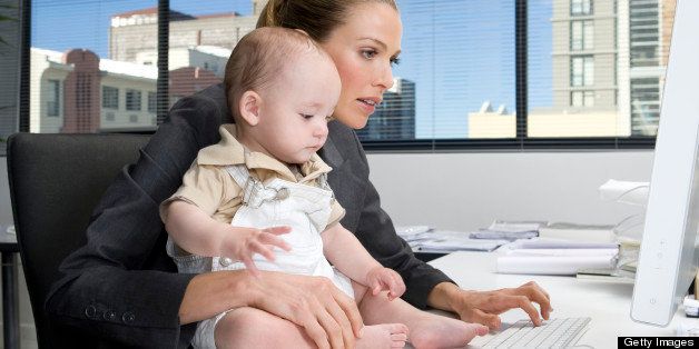 Busy mother holds her baby while typing.