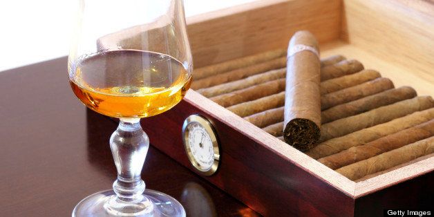 Fine Cuban cigars and glass of rum on wooden table