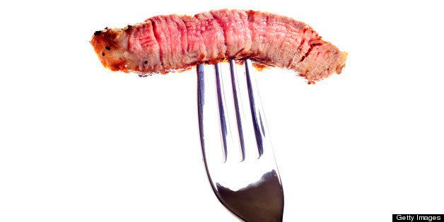 Juicy Grilled Steak on a Fork on White Background.