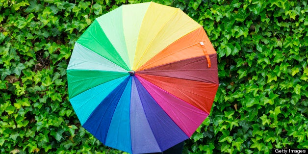 Young woman with playing with a colorful umbrella in a rainy day.