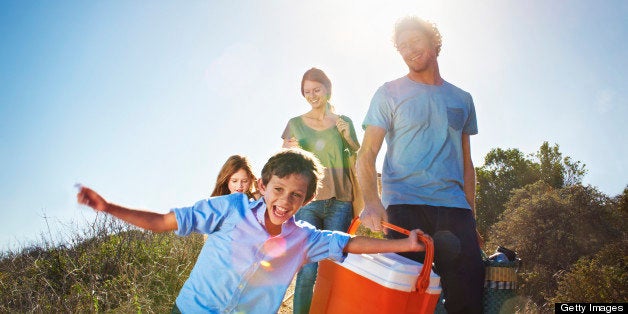 Family walking with picnic paraphernalia in park