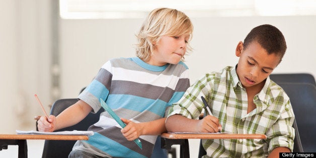 Little boy peeping in classmates examination paper