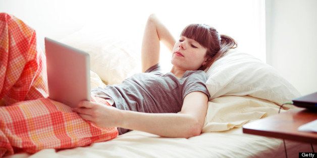 Young Woman Laying In Bed With Tablet