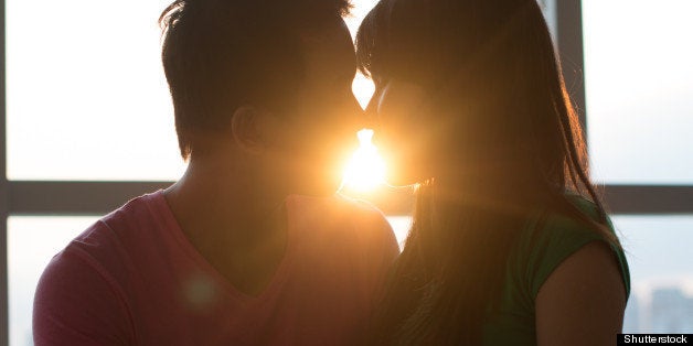 Young couple kissing on sofa with sunset in the background