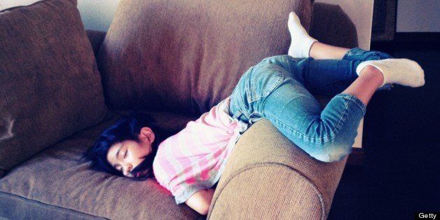 A girl is sleeping on couch in strange position.