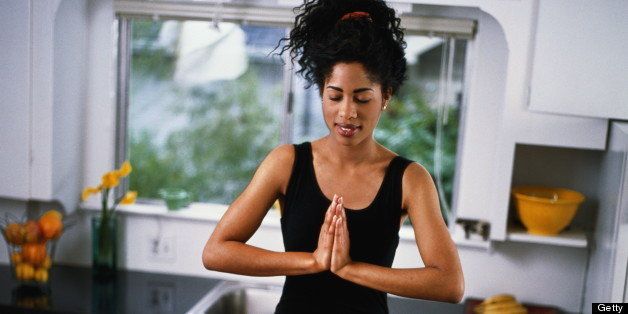 Young woman on kitchen table, in yoga position with candles