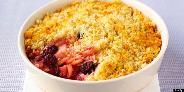 Apple and blackberry brown betty in white bowl on table, close-up