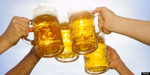 Close-up of people toasting beer mugs on sunny day
