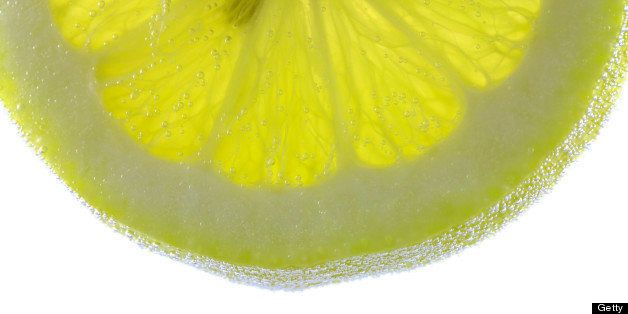 lemon slice on water with bubbles isolated on white background, studio shot.