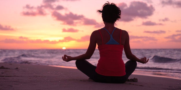 A woman doing yoga on the beach at sunset.More yoga images: