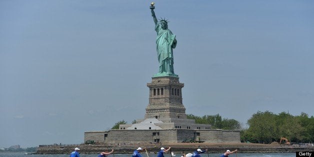 Paddlers from the Washington Canoe Club in an outrigger canoe pass the Statue of Liberty during the Hawaiian Airlines Liberty Challenge race June 22, 2013 in New York harbor. The traditional water sport in Polynesian culture is in its 17th year of competition in New York. AFP PHOTO/Stan HONDA (Photo credit should read STAN HONDA/AFP/Getty Images)