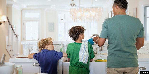 Rear view of children and father washing dishes at kitchen sink