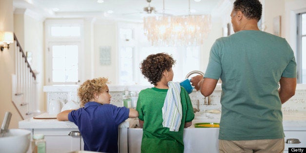 Rear view of children and father washing dishes at kitchen sink