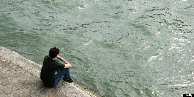 a guy sitting on the edge of the seine