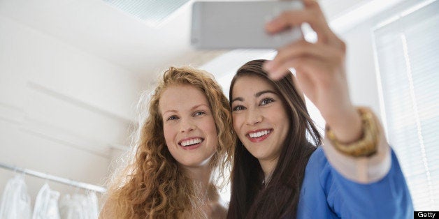 Young woman taking pictures with friend at bridal store