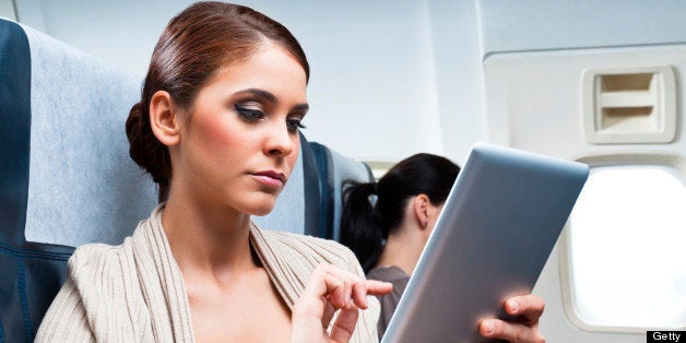 Young woman sitting on the airplane and using a digital tablet.